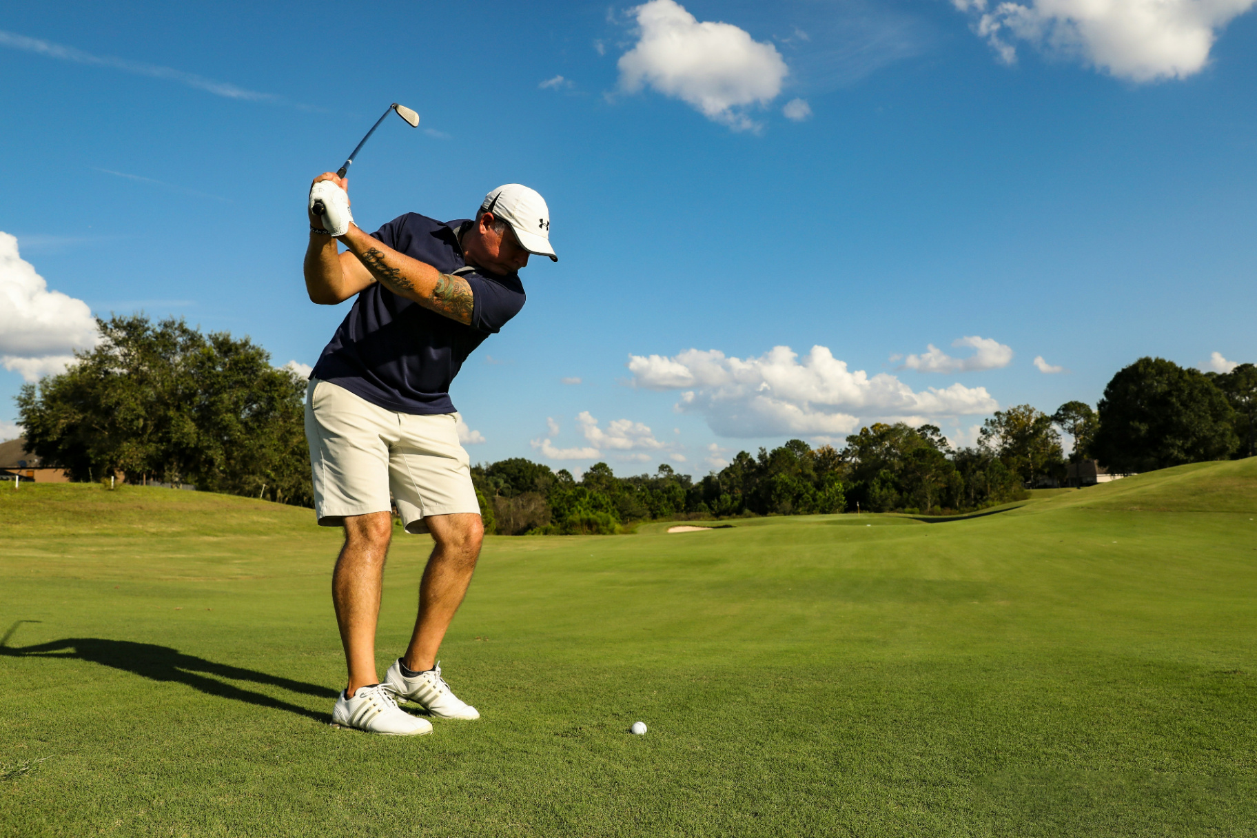 Senior golfer mid-swing on beautiful golf course